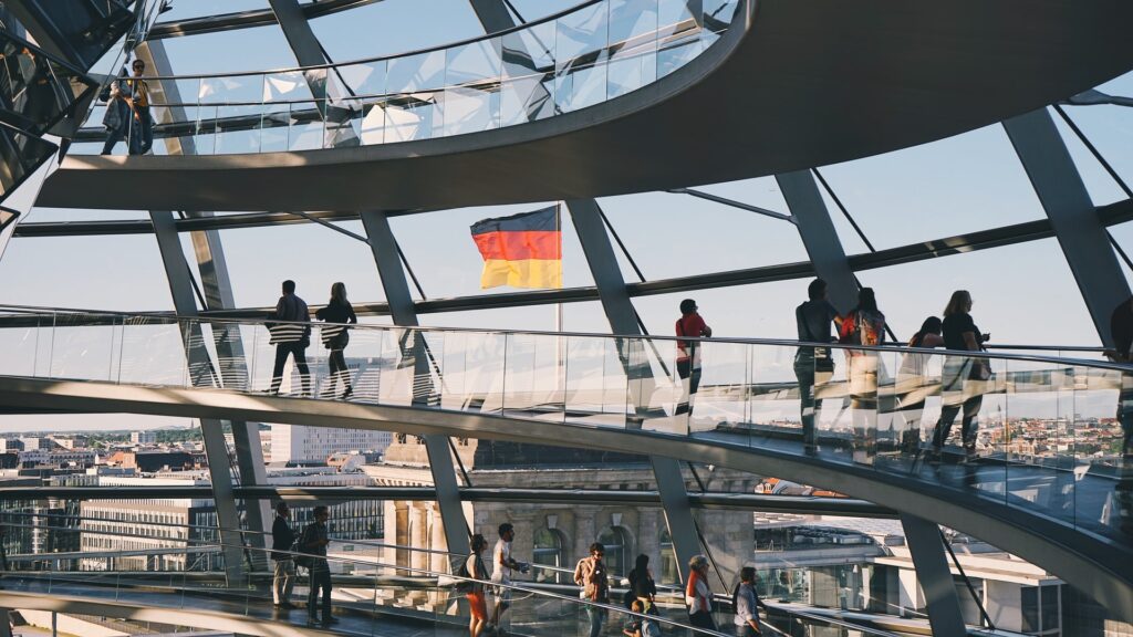 Image of business people walking through a building lobby with German flag outside